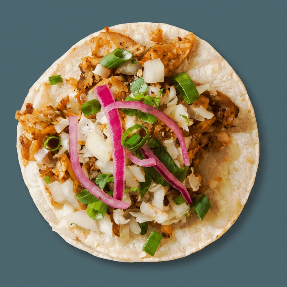 Overhead view of a soft taco filled with seasoned meat, diced onions, green onions, cilantro, and pickled red onions.
